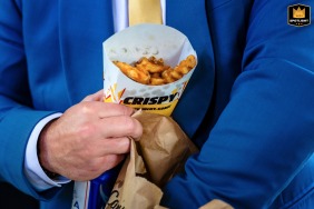   During portraits in Camarillo, CA, a groomsman indulges in a fast food snack, sneaking a playful bite and adding a humorous touch to the wedding festivities.
